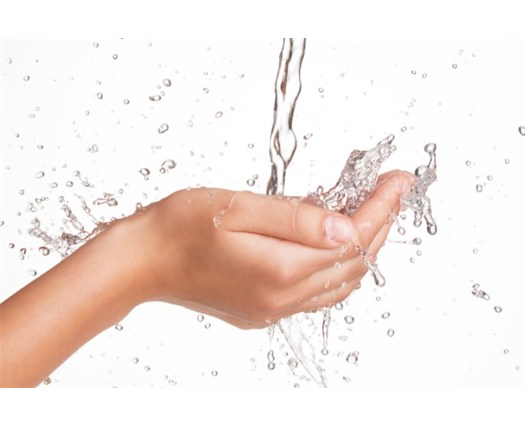 Hands under flowing water representing well-water treatment concerns